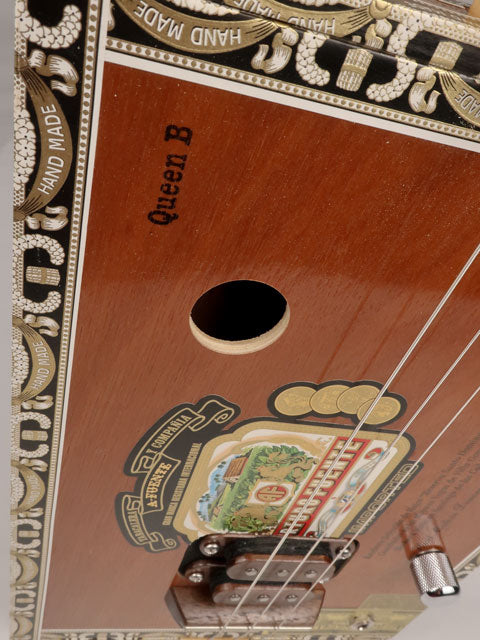 Front view of a 3 string cigar box guitar made with a Queen B Fuente cigar box. This cigar box guitar is handmade by Mike Snowden of Snowden Guitars.
