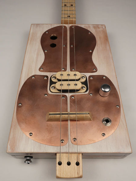 Front view Cigar Box Guitar instrument with copper pick guard on a gray background. This 3 string is made by Mike Snowden.
