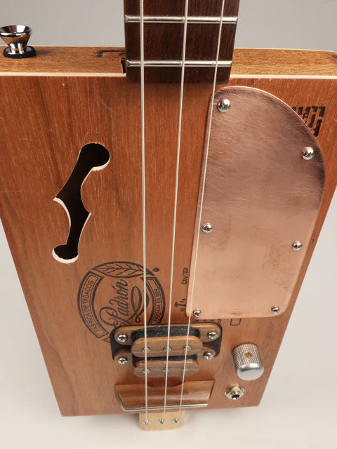 Front tilted view of a cigar box guitar with copper pick guard and f hole. Padron cigar box guitar made by Mike Snowden.