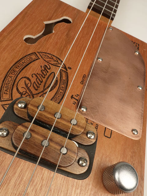 Tilted view cigar box guitar with humbucker and copper pick guard. Padron box made by Mike Snowden.