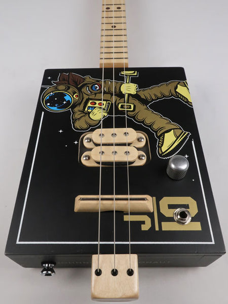 Front view of a 3 string cigar box guitar with an astronaut space suit on the front. Maple neck and maple humbucker pickup handmade by Mike Snowden of Snowden Guitars.