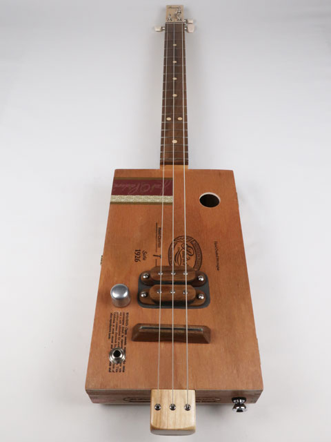 Front view of a 3 string cigar box guitar made with a Padron cigar box. This cigar box guitar is made with a walnut humbucker pickup and walnut fretboard. Handmade by Mike Snowden of Snowden guitars.