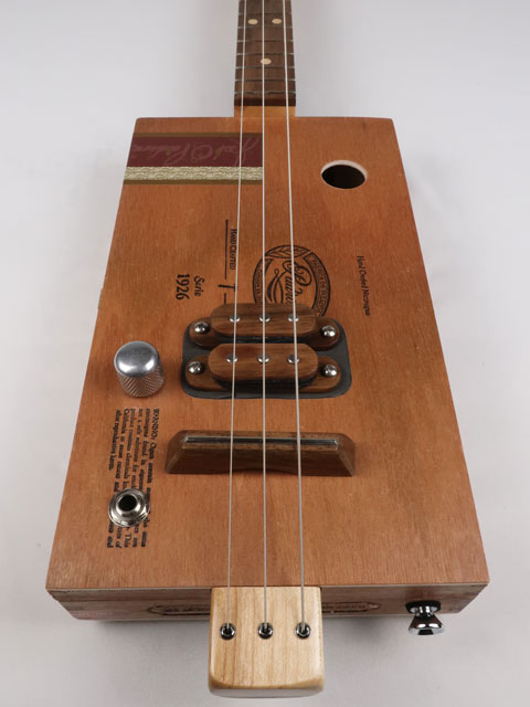 Front view of a 3 string cigar box guitar made with a Padron cigar box. This cigar box guitar is made with a walnut humbucker pickup and walnut fretboard. Handmade by Mike Snowden of Snowden guitars.