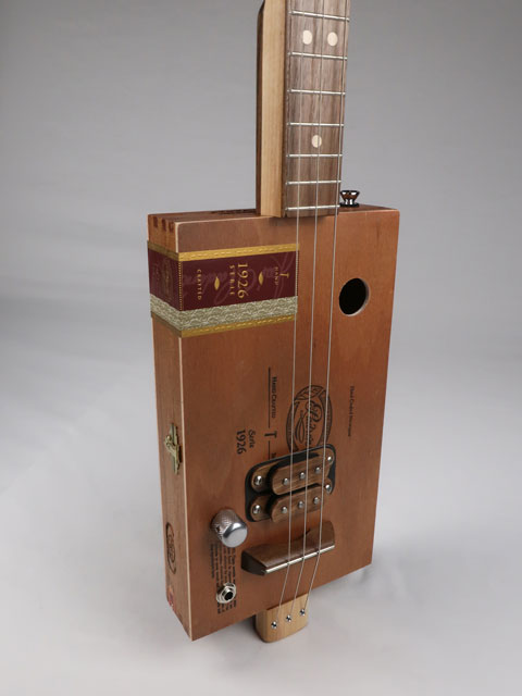 Front view of a 3 string cigar box guitar made with a Padron cigar box. This cigar box guitar is made with a walnut humbucker pickup and walnut fretboard. Handmade by Mike Snowden of Snowden guitars.