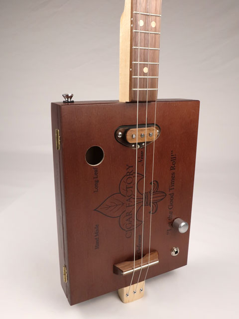Front tilted view of a 3 string cigar box guitar handmade by Mike Snowden of Snowden Guitars. This CBG is made with a New Orleans Cigar Factory cigar box.