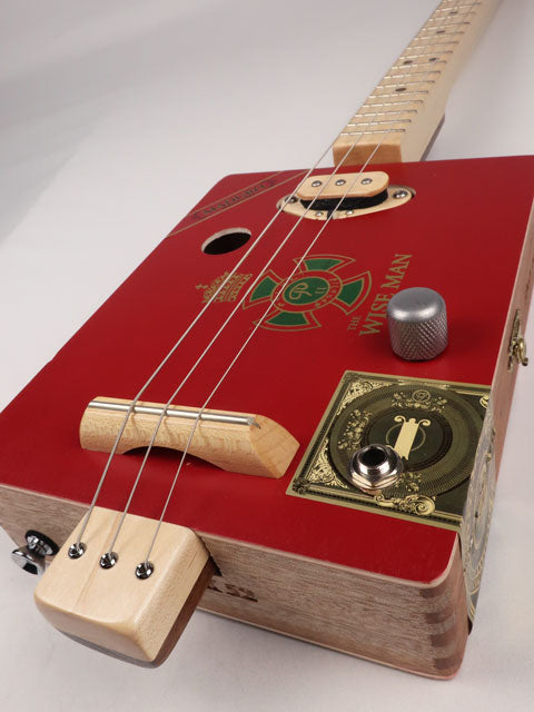 Front tilted view of The Wise Man 3 string cigar box guitar handmade by Mike Snowden. This cigar box is made with a red cigar box with The Wise Man printed on the front.