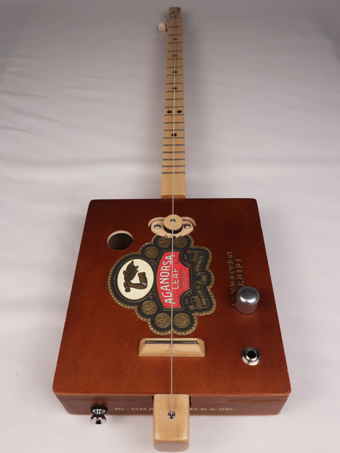 Front view of a single string diddly bow cigar box guitar made with a Aganorsa Leaf cigar box. Handmade by Mike Snowden of Snowden Guitars.