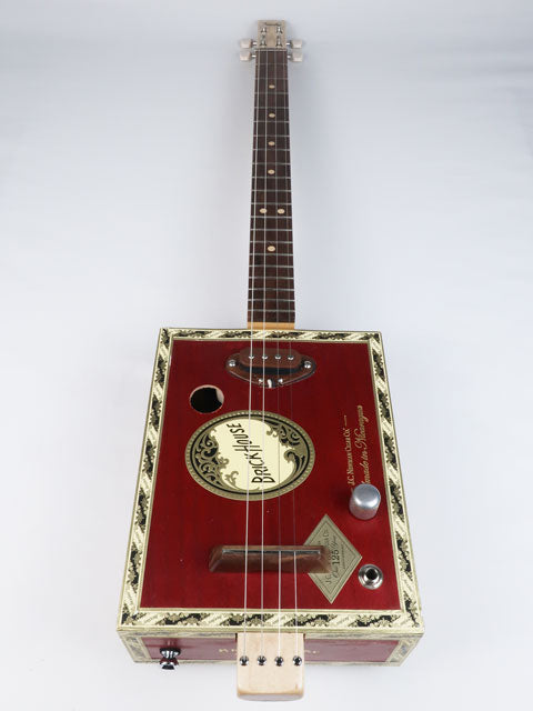 Front view of a 4 string cigar box guitar made with a Brick House cigar box and a walnut single coil pickup. This red cigar box guitar has a walnut fretboard and maple neck handmade by Mike Snowden.