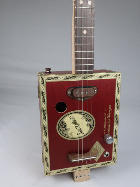 Front tiled view of a 4 string cigar box guitar made with a Brick House cigar box and a walnut single coil pickup. This red cigar box guitar is handmade by Mike Snowden.