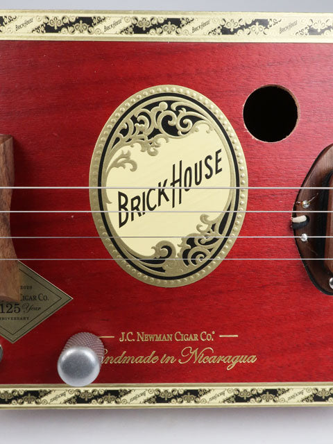 Close up front view of a 4 string cigar box guitar made with a Brick House cigar box and a walnut single coil pickup. This red cigar box guitar is handmade by Mike Snowden.