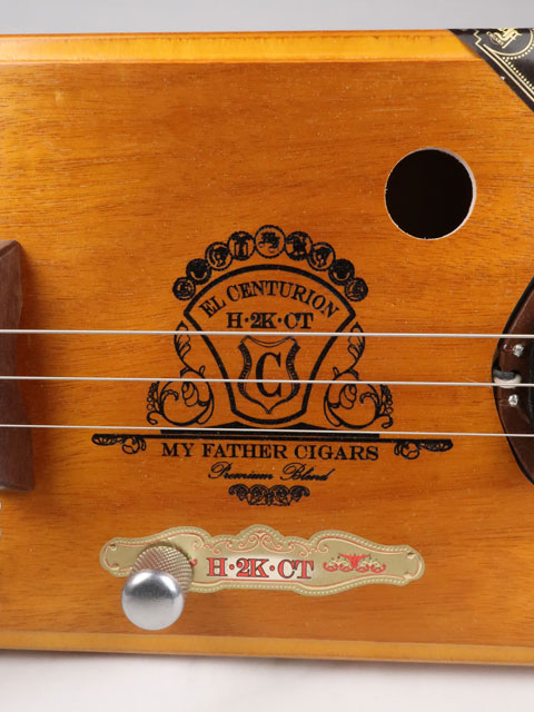 Close-up view of a 3 string Cigar Box Guitar made with a walnut single coil pickup. This cigar box guitar was handmade by Mike Snowden of Snowden Guitars.
