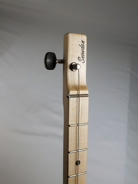 Close up view of a cigar box guitar headstock. Maple one string headstock with a Snowden Guitars logo on the front.