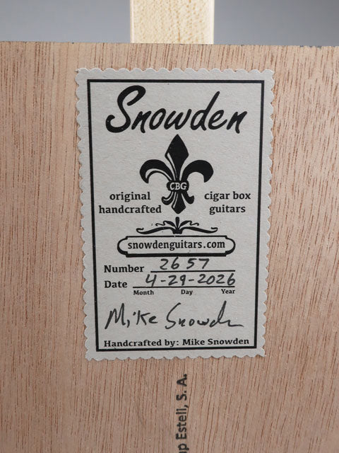 Close-up back view of a cigar box guitar sticker of the maker. This sticker shows the date and number made by builder mike Snowden of Snowden Guitars.