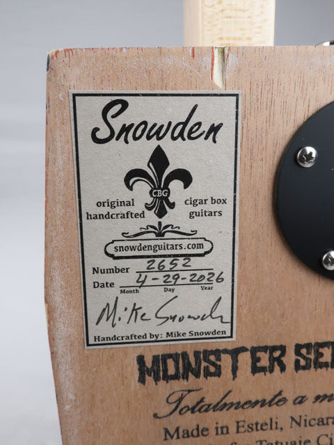 Back view of a cigar box guitar with a Snowden Guitars logo sticker on the back. the sticker shows the date and number of cigar box guitar made by Mike Snowden.