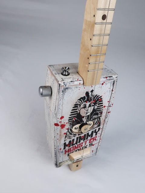 Front tiled view of a cigar box guitar made from a coffin shaped Mummy Monster cigar box. This one string diddly bow is handmade by Mike Snowden and as an Egyptian Pharos on the front. 