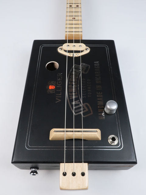 Front view of a 3 string cigar box guitar with a maple single coil pickup. Villigaer La Vencedora logo printed in silver on a black cigar box. This cigar box guitar is handmade by Mike Snowden.