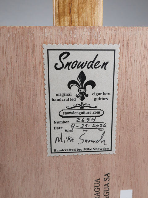 Back view of a cigar box guitar with a snowden guitars sticker on the back. The Sticker shows the date and number of this cigar box guitar.