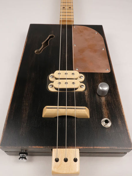 Front view of a 3 string cigar box guitar with a copper pick guard and maple humbucker. This cigar box guitar is handmade by Mike Snowden of Snowden Guitars.