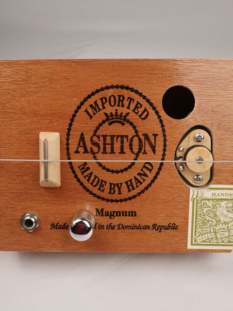 Close up front view of a Cigar Box Guitar diddly bow one string handmade by Mike Snowden. This cigar box guitar is made with an Ashton cigar box by Mike Snowden of Snowden Guitars.