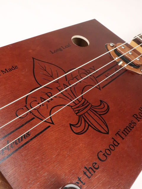 Front view of a 3 string cigar box guitar made with a New Orleans cigar factory cigar box. Handmade by Mike Snowden of Snowden Guitars.